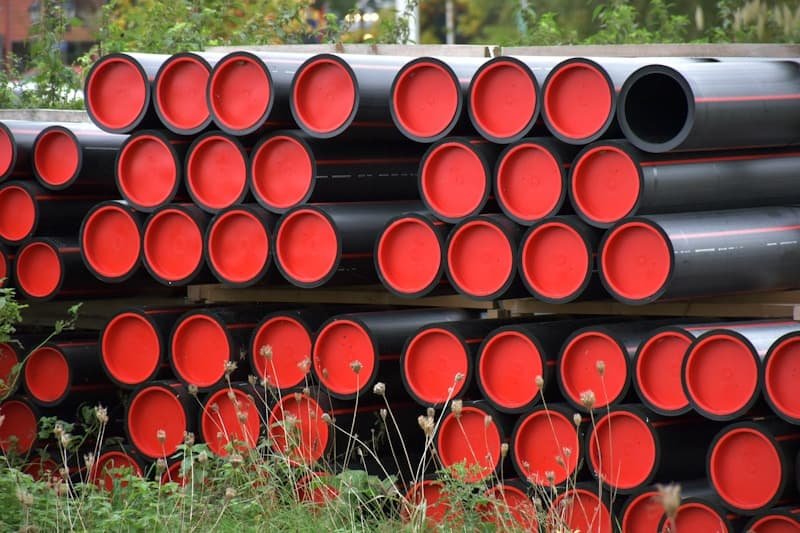Stacked plastic pipes with sealed end caps at a materials yard