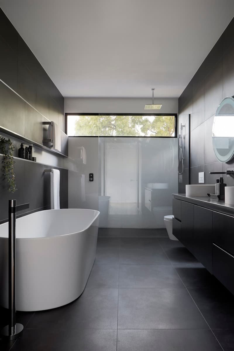Large-format dark porcelain floor and wall tiles in a finished bathroom